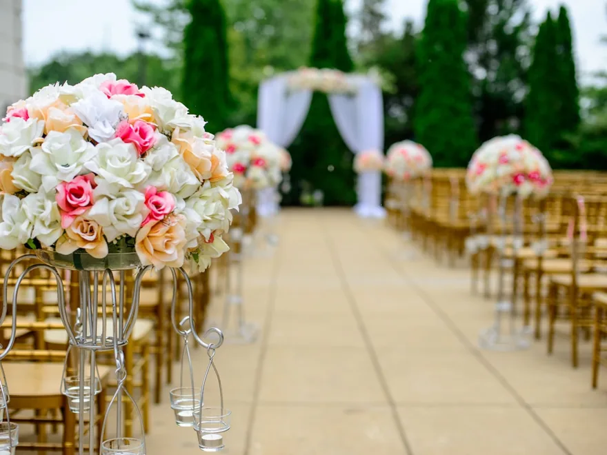 A wedding ceremony aisle lined with floral arrangements and gold chairs.